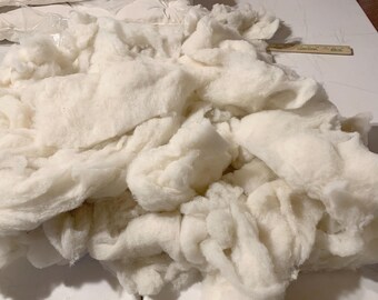 May include: A large pile of white cotton batting, a fluffy and soft material often used for stuffing pillows, cushions, and other crafts.