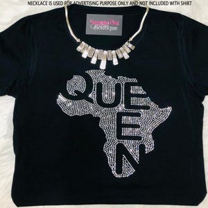 Op de afbeelding: Zwart T-shirt met een strass-ontwerp van het Afrikaanse continent en het woord "QUEEN" erop. De ketting is niet inbegrepen.