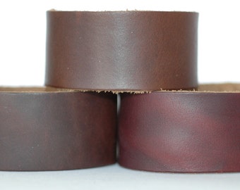 May include: Three leather wrist cuffs in different shades of brown. The top cuff is a dark brown, the middle cuff is a medium brown, and the bottom cuff is a reddish brown.
