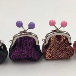 May include: Four small coin purses with different colored accents and patterned fabric. The purses are made of leather and have a metal clasp.