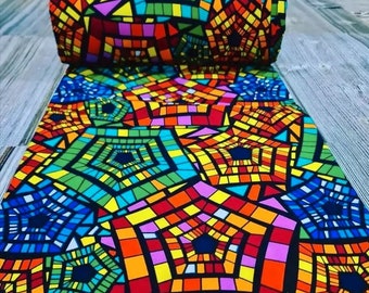 Könnte beinhalten: Bunter Stoff mit einem geometrischen Muster aus Quadraten und Rechtecken in Rot-, Orange-, Gelb-, Grün-, Blau- und Rosatönen. Das Muster ähnelt Buntglas.