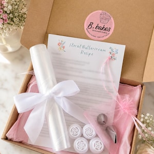 Peut inclure: Une boîte en carton contenant une fiche recette de crème au beurre florale, une poche à douille en plastique transparent roulée avec un ruban en satin blanc, quatre douilles en plastique blanc et deux douilles en métal dans un sachet en organza rose.