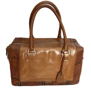 May include: A brown leather handbag with a snakeskin pattern on the sides and bottom. The bag has two top handles and a zipper closure.