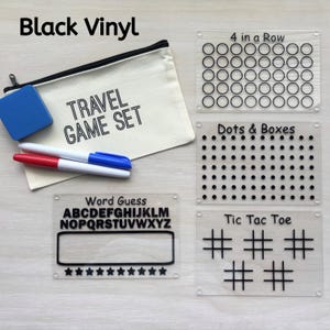May include: A travel game set with a canvas bag, blue eraser, and markers. Includes acrylic game boards for "4 in a Row", "Dots & Boxes", "Word Guess", and "Tic Tac Toe". The text "Black Vinyl" and "TRAVEL GAME SET" are visible.