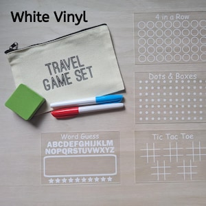 May include: A travel game set with a canvas pouch, eraser, and markers. Includes clear acrylic game boards for 4 in a Row, Dots & Boxes, Word Guess, and Tic Tac Toe. The pouch reads "TRAVEL GAME SET."