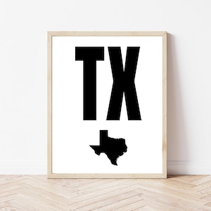 May include: Framed print featuring the letters "TX" in bold black font above a black silhouette of the state of Texas on a white background. The print is in a light wood frame.