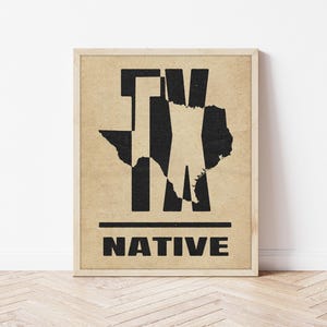 May include: Framed print featuring a black and white graphic design. The design includes the letters "TX" with the outline of the state of Texas, and the word "NATIVE" below. The print is in a light-colored wooden frame.