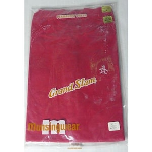 May include: A red t-shirt in a plastic bag. The shirt has the words "Grand Slam" in a gold font, the Munsingwear logo, and a small penguin logo. The words "Permanent Press" are printed at the top.