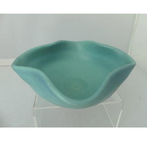 May include: A matte turquoise ceramic bowl with a distinctively wavy, scalloped rim. The bowl features a smooth, solid-colored finish and a wide, shallow basin, showcasing a fluid, organic shape that curves gently along the entire upper edge.