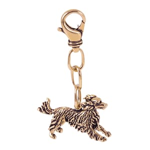 May include: Gold-colored metal keychain featuring a detailed, running dog charm. The dog is depicted with a fluffy coat and a long tail. The keychain has a spring-loaded clasp.