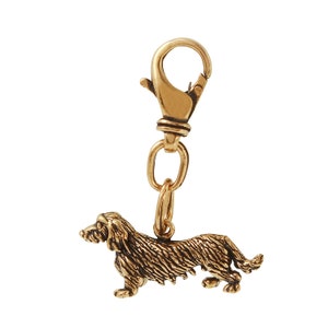 May include: A gold-colored dachshund dog charm with a split ring and a lobster clasp.
