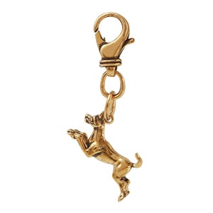 May include: Gold-toned metal charm featuring a detailed sculpture of a dog standing on its hind legs with its front paws raised. The charm is attached to a gold-toned metal lobster clasp.