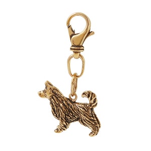 May include: A gold-toned metal keychain featuring a detailed, three-dimensional sculpture of a dog.