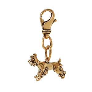 May include: Gold-toned metal charm of a small dog with a curly tail, attached to a gold-toned metal chain and a lobster clasp.