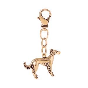 Op de afbeelding: Een gouden metalen sleutelhanger met een gedetailleerd beeldje van een hond. De sleutelhanger heeft een metalen lus en een ketting.