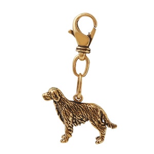 May include: Gold-toned metal keychain featuring a detailed golden retriever dog charm attached to a lobster clasp.