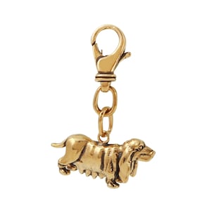 May include: Gold-toned metal keychain featuring a detailed, three-dimensional sculpture of a basset hound.