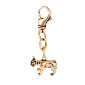 May include: Gold-toned metal keychain featuring a small, detailed figurine of a French bulldog. The keychain has a lobster clasp.