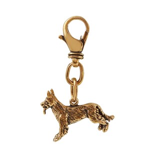May include: A gold-colored metal charm featuring a detailed depiction of a dog, likely a German Shepherd, attached to a lobster clasp. The charm is designed to be used as a keychain or pendant, showcasing a realistic canine figure.