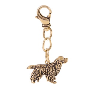May include: A gold-colored metal keychain featuring a detailed, three-dimensional sculpture of a Cocker Spaniel dog.