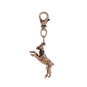 May include: A gold-toned metal keychain featuring a detailed sculpture of a boxer dog in a jumping pose. The keychain has a spring-loaded clasp.