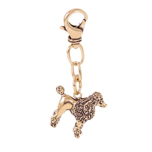 May include: Gold-toned keychain featuring a detailed poodle charm with a textured surface. The keychain has a lobster clasp.