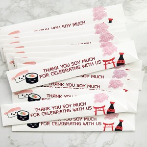 Puede incluir: Una pila de palillos de papel blanco con un dise&ntilde;o de sushi rojo y negro y el texto "Thank you soy much for celebrating with us".