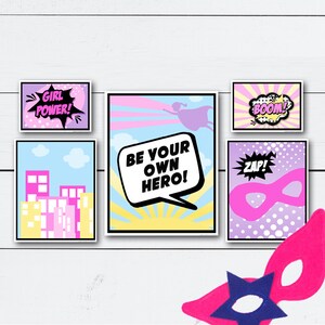 May include: Five printable posters with a superhero theme. The posters feature a pink and blue color scheme with text that says "Girl Power!" "Be Your Own Hero!" "Boom!" "Zap!" and a silhouette of a superhero flying.