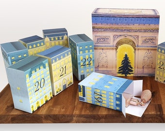 Puede incluir: Un calendario de adviento navideño con temática parisina. El calendario presenta una combinación de colores azul y amarillo y tiene la forma de una serie de pequeños edificios. El calendario está abierto para revelar una pequeña caja con el número 6. El calendario está sobre una superficie de madera. El texto "Christmas In Paris" y "Advent Calendar" está en la parte superior de la imagen. El texto "Papier Bonbon" está en la parte inferior de la imagen.