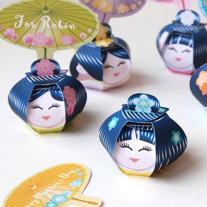 May include: Five colorful Kokeshi paper doll favor boxes with different messages on the top. The messages include "For Robin", "Made with Love", "I Love You", "Happy Birthday", and "Happy Mother's Day".