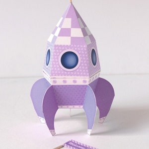 May include: Purple paper rocket with a checkered top and a white flag that says "It's a Boy!" and a second flag that says "Welcome Baby Boy!"