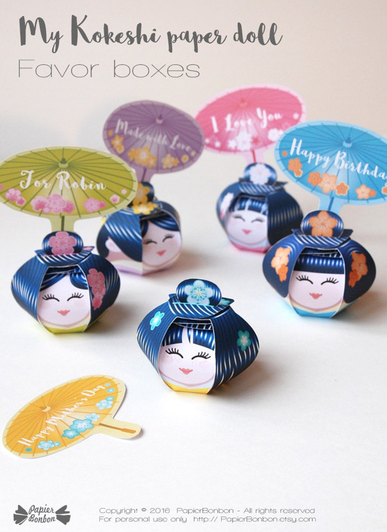 May include: Five colorful Kokeshi paper doll favor boxes with different messages on the top. The messages include "For Robin", "Made with Love", "I Love You", "Happy Birthday", and "Happy Mother's Day".