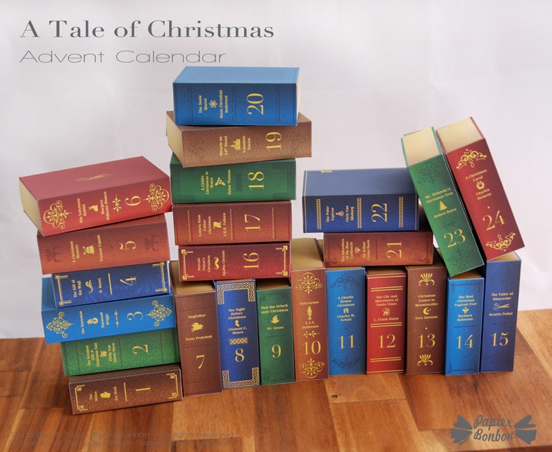 Puede incluir: Un calendario de adviento de Navidad hecho de peque&ntilde;as cajas con forma de libro apiladas en forma de pir&aacute;mide. Las cajas est&aacute;n decoradas con letras doradas e ilustraciones. Los n&uacute;meros del 1 al 24 son visibles en las cajas.