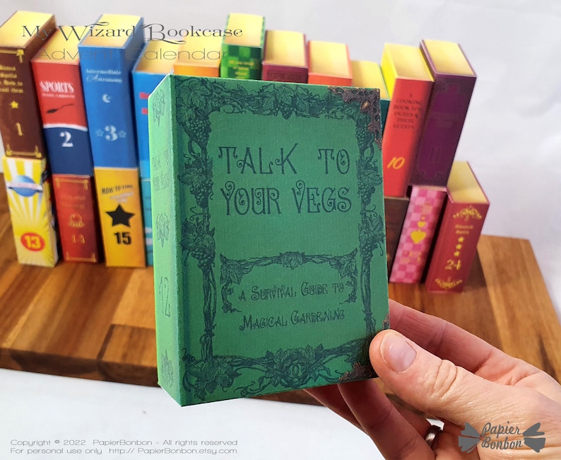 May include: A green book with the title "TALK TO YOUR VEGS" and the subtitle "A Survival Guide to Magical Gardening". The book is part of a set of miniature books that are arranged in a bookcase.