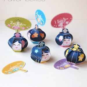 May include: Five colorful Kokeshi paper doll favor boxes with different messages on the top. The messages include "For Robin", "Happy Birthday", "I Love You", "Happy Mother's Day", and "Made with Love".