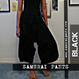 May include: A woman wearing a black tank top and black samurai pants. She is also wearing a black beanie with a Canadian flag patch. The text "SAMURAI PANTS" and "BLACK" are visible in the image.