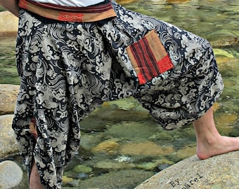 May include: Black and white patterned pants with a red and brown patch pocket. The pants are loose fitting and have a wide leg. The pants are worn by a person standing in a stream with rocks.