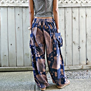 May include: A grey sleeveless ribbed top paired with loose-fitting navy blue trousers featuring a light brown fan and floral pattern. The trousers have an elasticized waistband and two large side cargo pockets with visible stitching details.