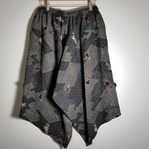 Puede incluir: Pantalones de pierna ancha con estampado en blanco y negro con un dise&ntilde;o geom&eacute;trico y flores rojas. Los pantalones tienen una pierna ancha y un ajuste holgado.