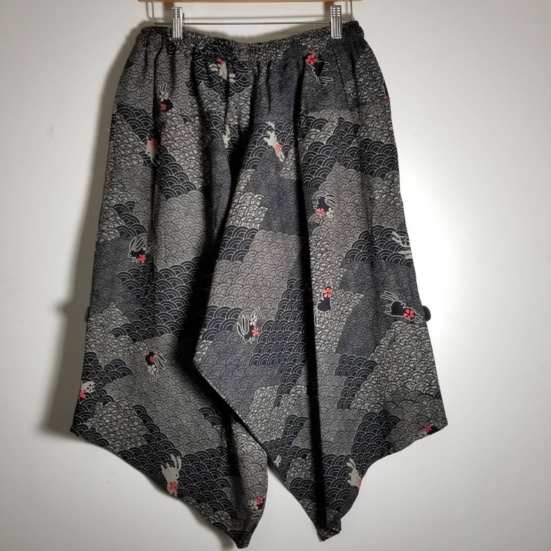 Puede incluir: Pantalones de pierna ancha con estampado en blanco y negro con un dise&ntilde;o geom&eacute;trico y flores rojas. Los pantalones tienen una pierna ancha y un ajuste holgado.