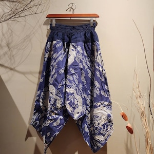 May include: Blue and white patterned pants with a dragon design. The pants have a wide leg and a loose fit.