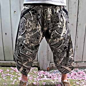 May include: Black and white patterned pants with a loose, wide-leg fit. The pants have a drawstring waistband and are made of a lightweight fabric.