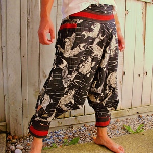 May include: Black and white patterned trousers with a red waistband and trim. The trousers feature a koi fish design and a loose fit. Made from lightweight fabric, ideal for warmer weather. The waist is approximately 76 cm.