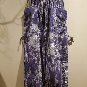 Może przedstawiać: Fioletowe spodnie z białym wzorem smoka i chmur.