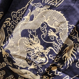 May include: A navy blue fabric with a white dragon design. The dragon is depicted in a traditional Chinese style, with swirling clouds and intricate details.