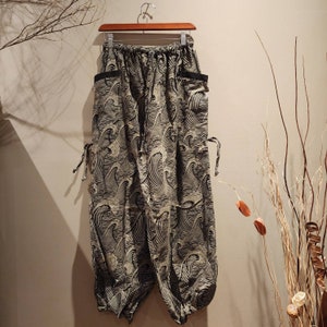 May include: Black and white patterned pants with a drawstring waist and side pockets. The pants have a loose, flowing fit and are made of a lightweight fabric.