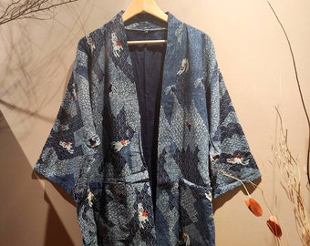 May include: A blue and white patterned kimono with a dark blue lining. The kimono has a traditional Japanese design with a wave pattern and a fish motif.