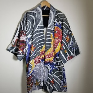May include: A black and white kimono with a colorful koi fish and wave design. The kimono has a black lining and is made of a lightweight fabric.