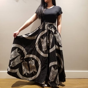 May include: A black and white maxi skirt with a circular pattern of arrows. The skirt is made of a soft, flowing fabric and has a drawstring waist.