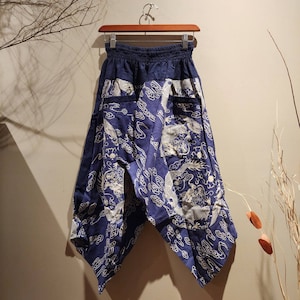 May include: Blue and white patterned pants with a wide leg and an elastic waistband. The pants have a dragon design and are made of a lightweight fabric.
